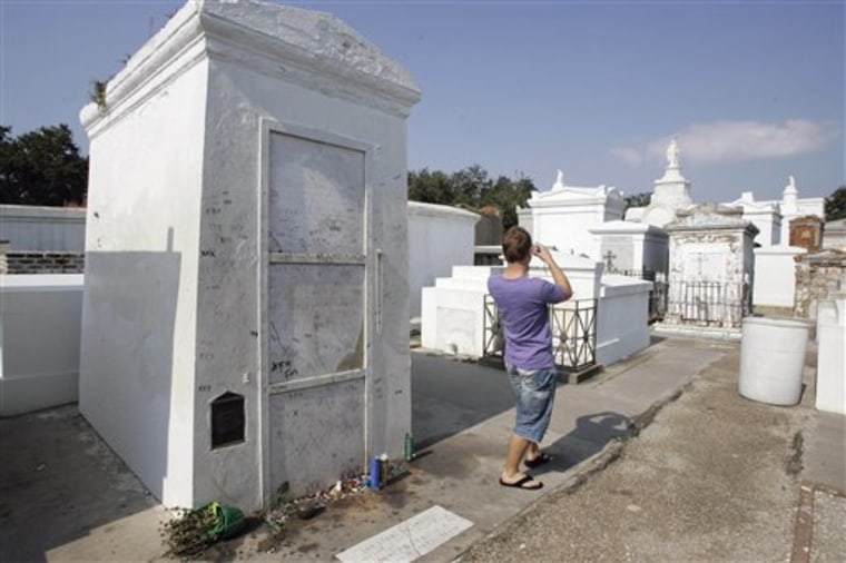 This Sept. 29, 2008, file photo shows a visitor as he takes a photograph of St. Louis Cemetery No. 1 with his back to what is believed to be the tomb of famous Voodoo priestess Marie Laveau, left, on the edge of the French Quarter in New Orleans. 
